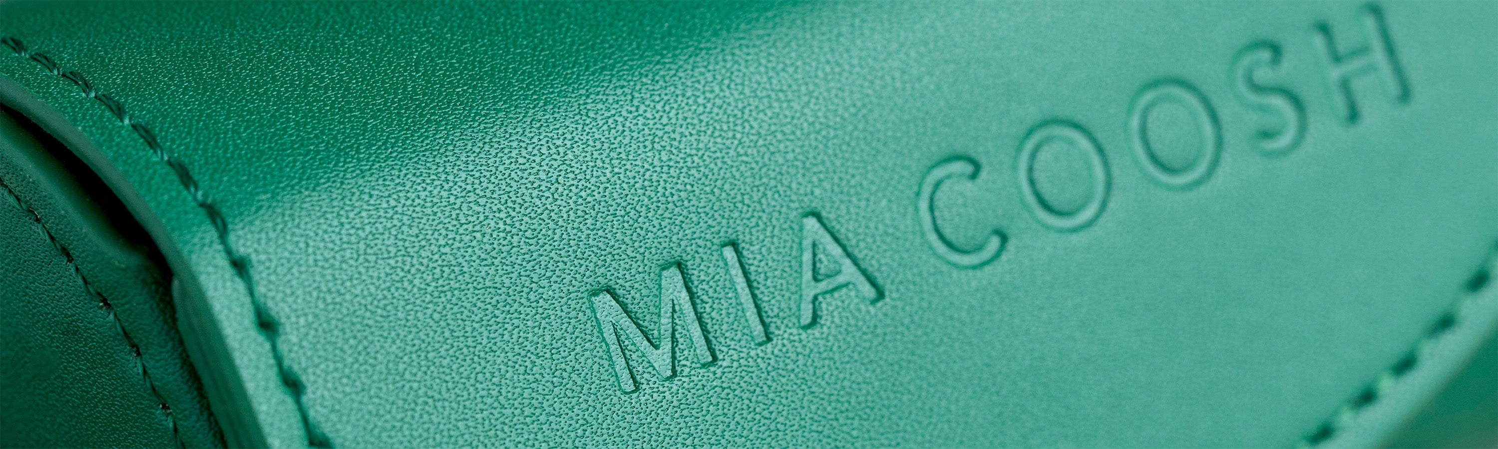 Closeup of Emerald Green microfibre leather with 'MIA COOSH' embossed logo