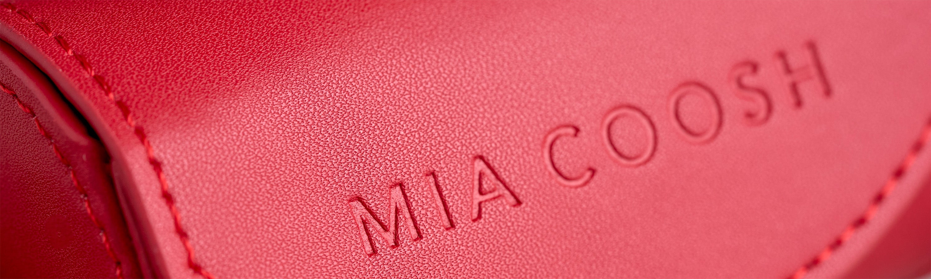 Closeup of Rouge Rad microfibre leather with 'MIA COOSH' embossed logo