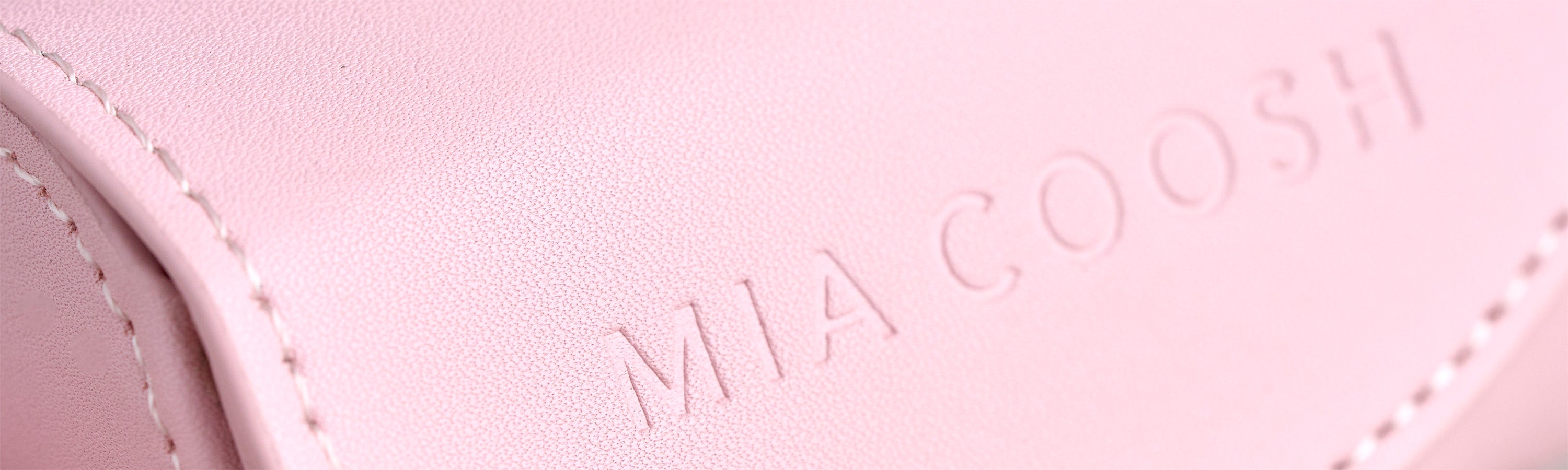 Closeup of Blush Pink microfibre leather with 'MIA COOSH' embossed logo