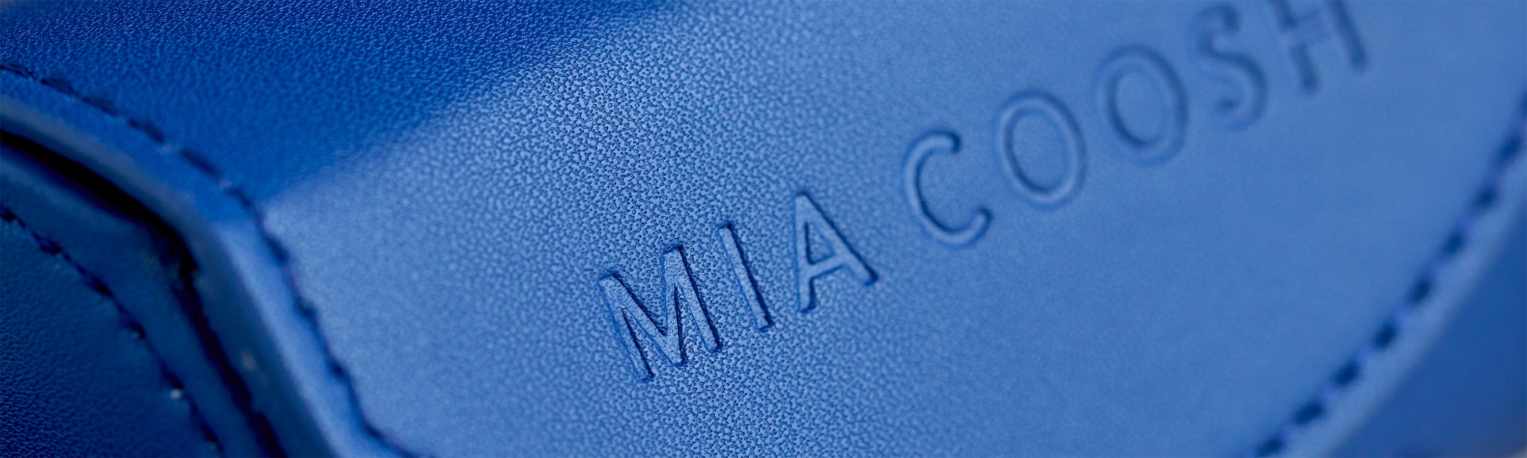 Closeup of Navy Blue microfibre leather with 'MIA COOSH' embossed logo