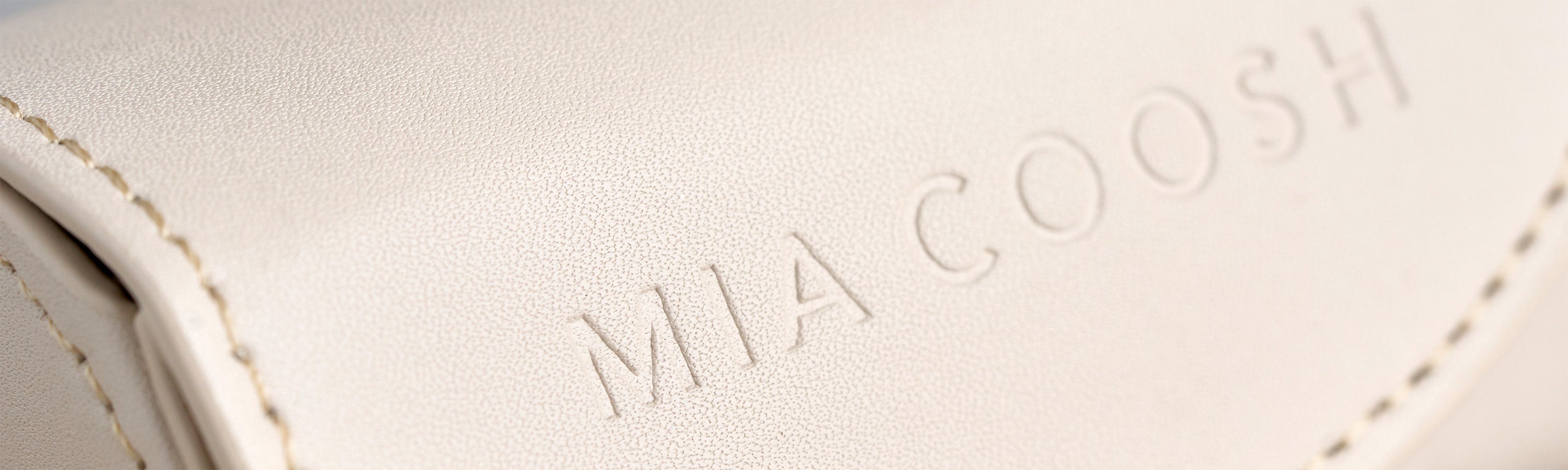 Closeup of Vanilla Cream microfibre leather with 'MIA COOSH' embossed logo